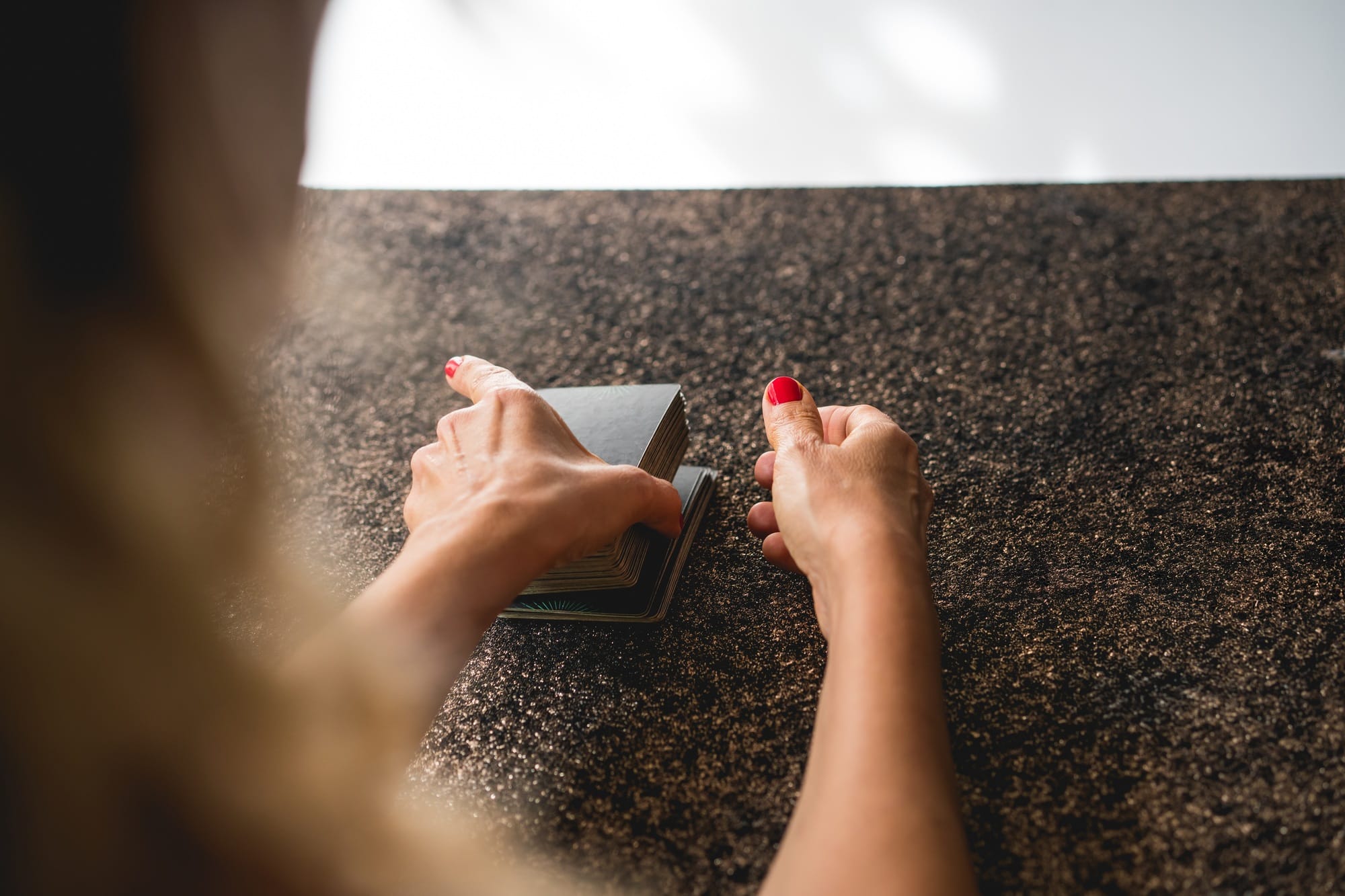 Shoulder view of a tarot reader blending the cards, preparing for an insightful reading